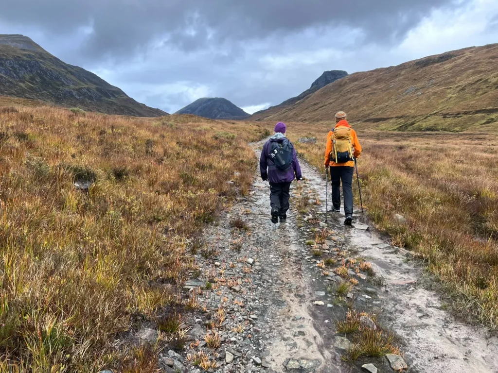 Two walkers on the track with the hills ahead